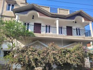 a white house with a balcony and trees at Most Spacious Stay in Shānti Niketan