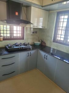 a kitchen with white cabinets and a stove at Most Spacious Stay in Shānti Niketan