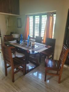 a dining room table with chairs and a wooden floor at Most Spacious Stay in Shānti Niketan