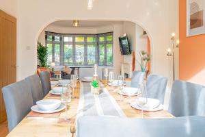 a dining room with a long table and blue chairs at 4-bed Retreat, Spacious Oasis With Modern Comfort in Southampton