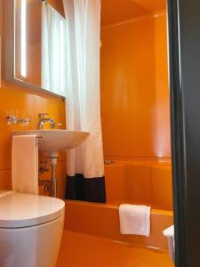 baño de color naranja con lavabo y aseo en Eva's Seeblick, en Krattigen