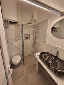 a bathroom with a toilet and a glass shower at Apartmani Milka S in Bar