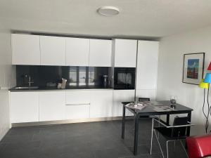 a kitchen with white cabinets and a table at Villa Bootsmann mit spektakulärer Seesicht nahe Badestrand in Vitznau