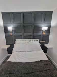 1 dormitorio con 1 cama blanca grande y 2 luces en Delightful cabin retreat wrapped by natural beauty en Dartford