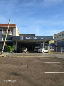 a building with a hotel management sign in a parking lot at Hotel Manzoni in Campo Grande