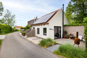 una pequeña casa blanca con techo solar en Hello Zeeland - Tiny Houses Groede, en Groede