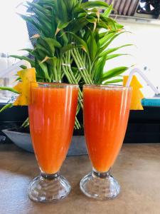 Dois copos de sumo de laranja sentados numa mesa. em Ceylanro Transit Villa em Negombo