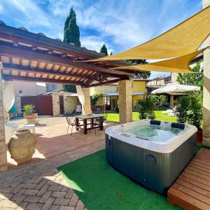 une terrasse avec un bain à remous sous une pergola en bois dans l'établissement Il Cortile delle Rose Holiday House, à Pérouse