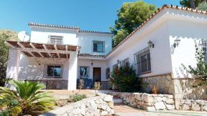 a white house with a stone wall at Villa Itaca in Mijas