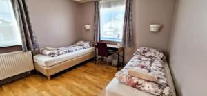 Habitación con 2 camas, escritorio y ventana. en Aurora Guesthouse en Grundarfjordur
