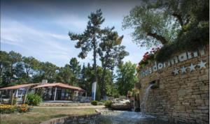 a building with a stone wall next to a water fountain at Détente et confort au Bois Dormant camping 4* MH240 in Saint-Jean-de-Monts