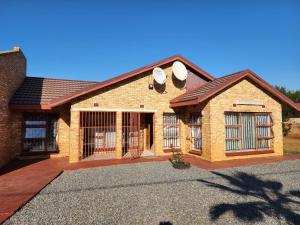 a brick house with two windows and a driveway at COMFORT ZONE GUEST HOUSE in Zeerust