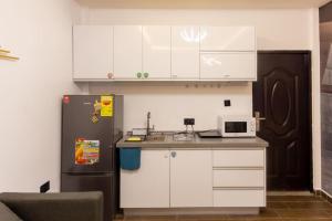 a kitchen with white cabinets and a black refrigerator at Petunia Apartment in Accra