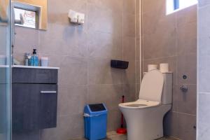 a bathroom with a toilet and a blue trash can at Petunia Apartment in Accra