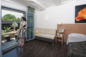 two women standing in a bedroom with a bed and a window at Relais Bellaria Hotel & Congressi in Bologna