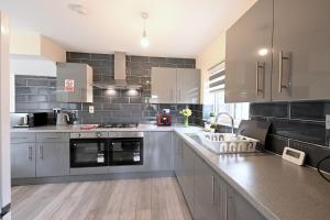 a large kitchen with stainless steel appliances and gray tiles at SPACIOUS 5 BEDROOM HOUSE NEXT TO TOTTENHAM STADIUM in London