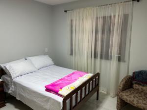 um quarto com uma cama com um cobertor rosa em Casa das Suculentas em Jaraguá do Sul