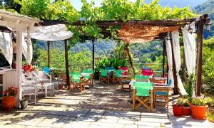 un patio con sillas, mesas y una pérgola en Odos Kentavron, en Tsagkarada