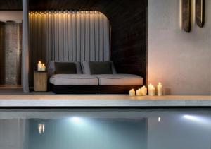 a couch sitting next to a swimming pool with candles at Grau Roig Andorra Boutique Hotel & Spa in Grau roig