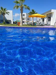 a large blue swimming pool with a yellow umbrella at Maison des Oliviers, Yasmine Hammamet, Bouficha in Hammamet Sud