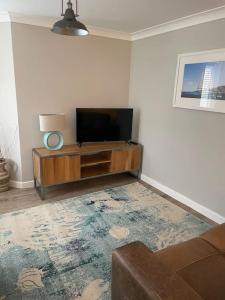 Una sala de estar con un televisor de pantalla plana en un centro de entretenimiento. en Seaside Modern Apartment, en Westward Ho 25 fotos más