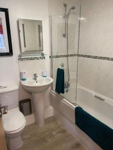 a bathroom with a sink and a toilet and a shower at Seaside Modern Apartment in Westward Ho +25 photos