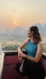 una donna seduta su un balcone che guarda il tramonto di Vangvieng Rock Backpacker Hostel a Vang Vieng