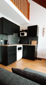 a kitchen with black cabinets and white appliances at Au Cordouan in Le Verdon-sur-Mer