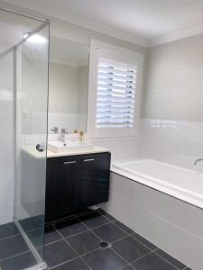 a bathroom with a tub and a sink and a shower at Happy life in Schofields