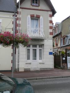 a white house with a balcony on a street at À l'Approche de la Mer in Houlgate
