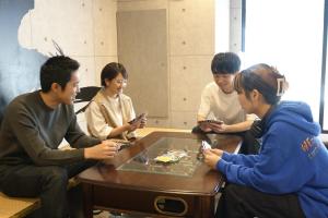 Un groupe de personnes assises autour d'une table pour regarder leurs téléphones portables dans l'établissement Hotel Tomariya Ueno, à Tokyo