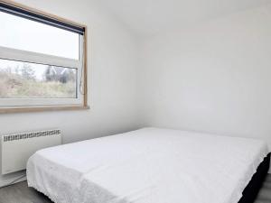 een witte slaapkamer met een bed en een raam bij Holiday home Blokhus LXVI in Blokhus
