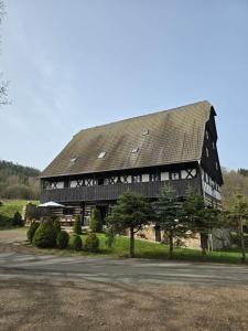 a large black and white building with a roof at Penzion Pod hradem in Adršpach