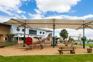 a park with a playground with an umbrella and a slide at The Pastures Holiday Lodge in Tattershall