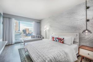 a bedroom with a white bed and a large window at Le Méridien Denver Downtown in Denver