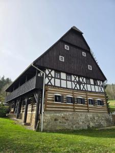 a large wooden barn with a black roof at Penzion Pod hradem in Adršpach