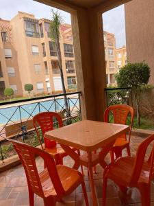 d'une table et de chaises sur un balcon avec vue sur un bâtiment. dans l'établissement RICO FLORES PALM BENSLIMANE, à Mohammedia