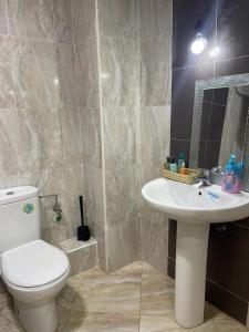 La salle de bains est pourvue de toilettes blanches et d'un lavabo. dans l'établissement RICO FLORES PALM BENSLIMANE, à Mohammedia