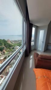 a living room with a couch and a large window at APARTEMEN THE BAY LAMPUNG CITY MALL in Bandar Lampung