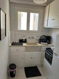 uma cozinha branca com um lavatório e uma janela em Sea View Apartments near Athens Airport em Artemida