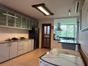 a large kitchen with white cabinets and a black refrigerator at Spacious BBQ Gathering Masai Megaria in Masai