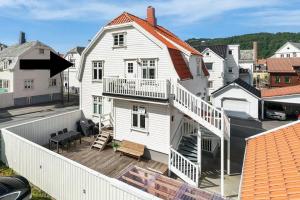 a white house with a porch and a balcony at Romslig 3-soveroms toppleilighet midt i sentrum in Egersund
