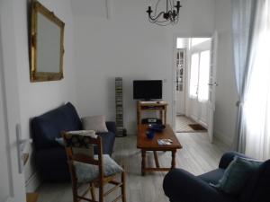 ein Wohnzimmer mit 2 blauen Stühlen und einem TV in der Unterkunft À l'Approche de la Mer in Houlgate