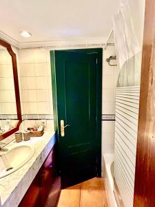 a green door in a bathroom with a sink and a tub at Apartamento en Ibiza in Cala San Vicente