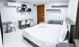 a white bedroom with a bed and a table and chairs at S&Y Apartment in Ban Nong Waeng