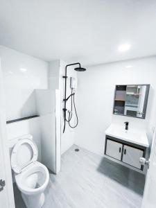 a white bathroom with a toilet and a sink at S&Y Apartment in Ban Nong Waeng