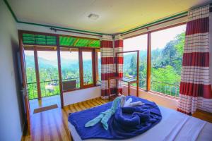 a person laying in a bed in a room withwindows at Ella Nine Arch lodge in Ella