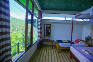 a room with a bed and a balcony with windows at Ella Nine Arch lodge in Ella