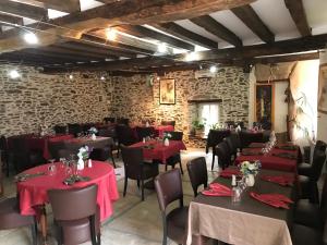 a dining room with tables and chairs with red tablecloths at La Longre in Cerisy-la-Forêt