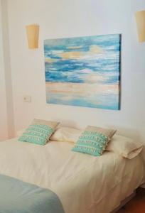uma cama com duas almofadas e um quadro na parede em Apartamento en Ibiza em Cala San Vicente